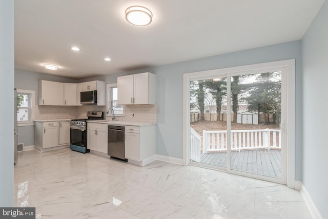 kitchen featuring white cabinets, backsplash, stainless steel appliances, and sink