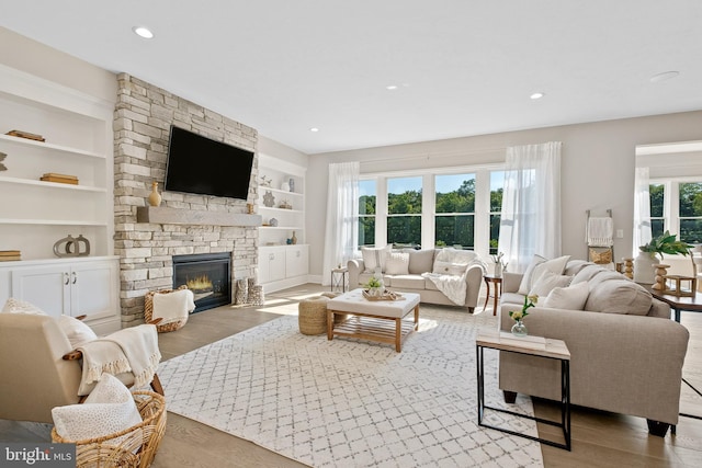 living room featuring light hardwood / wood-style flooring, a wealth of natural light, and a stone fireplace