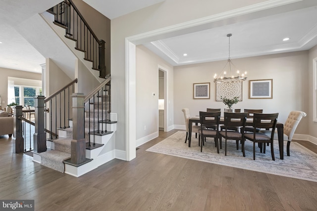 dining space featuring a raised ceiling, ornamental molding, dark wood-type flooring, and a chandelier