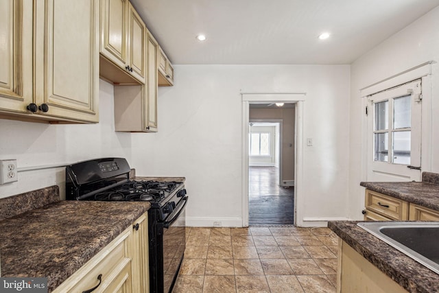 kitchen featuring light hardwood / wood-style floors, black gas range oven, and dark stone counters