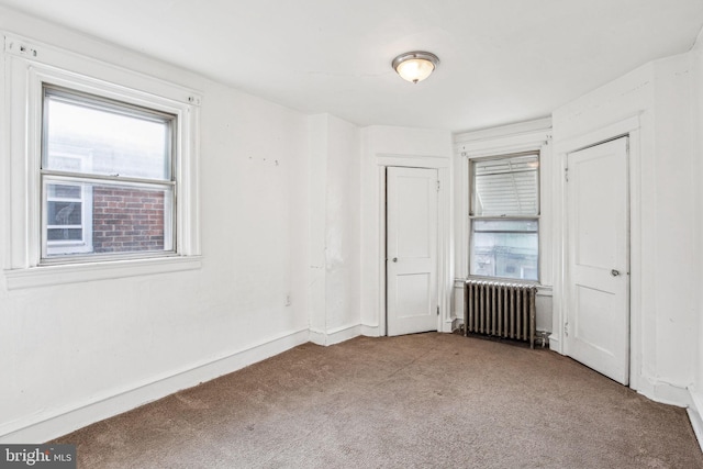 unfurnished room featuring light colored carpet and radiator heating unit