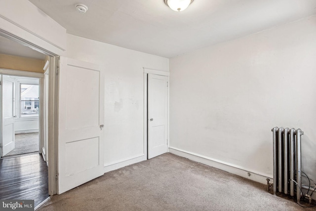 unfurnished bedroom featuring radiator heating unit and carpet