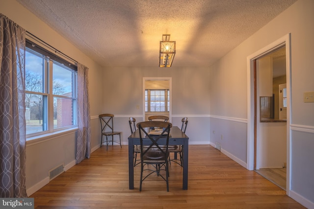 dining area with light wood-type flooring and a textured ceiling