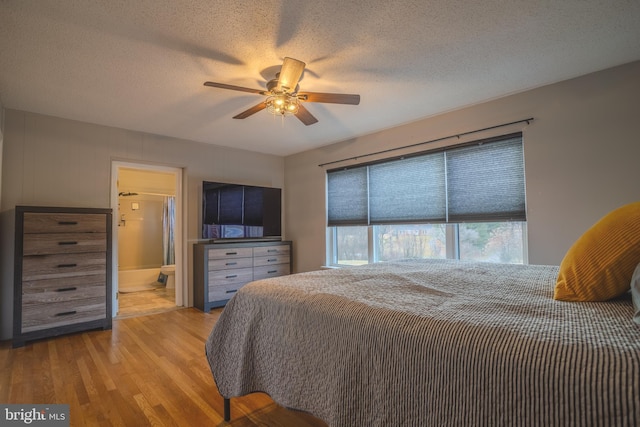 bedroom with a textured ceiling, ensuite bathroom, ceiling fan, and light hardwood / wood-style floors