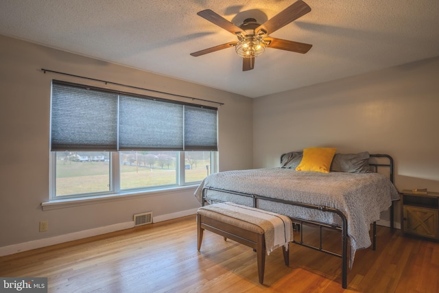 bedroom with ceiling fan, a textured ceiling, and light hardwood / wood-style flooring