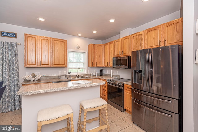 kitchen with stainless steel appliances, sink, light tile patterned floors, a center island, and a breakfast bar area