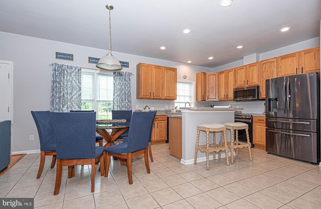 kitchen with pendant lighting, a center island, stainless steel appliances, and light tile patterned floors