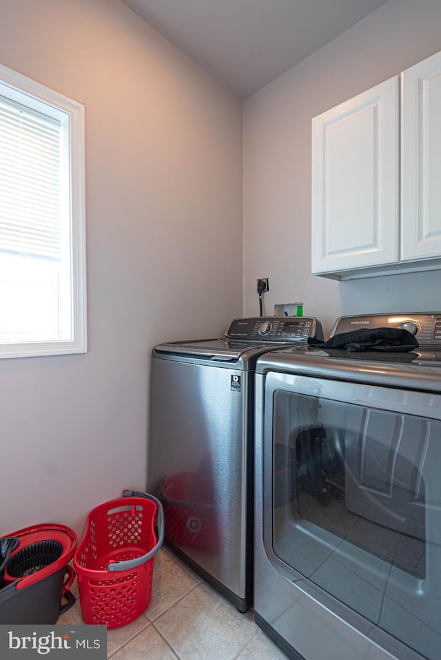 laundry area featuring cabinets, light tile patterned floors, and separate washer and dryer