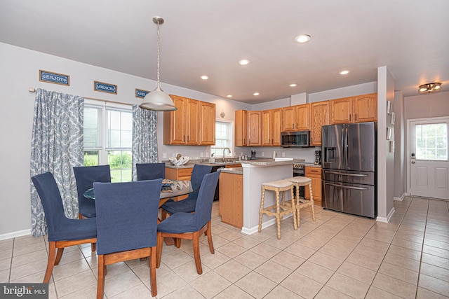 kitchen with a wealth of natural light, a kitchen island, pendant lighting, and appliances with stainless steel finishes