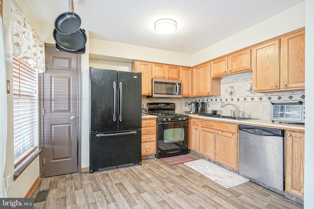 kitchen with light brown cabinetry, backsplash, sink, black appliances, and light hardwood / wood-style flooring