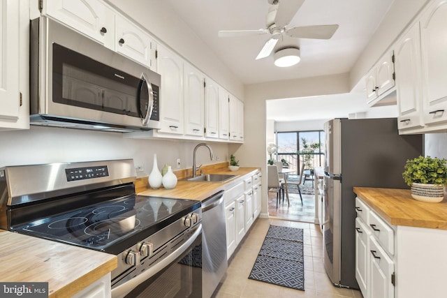 kitchen with light tile patterned floors, stainless steel appliances, white cabinetry, and sink