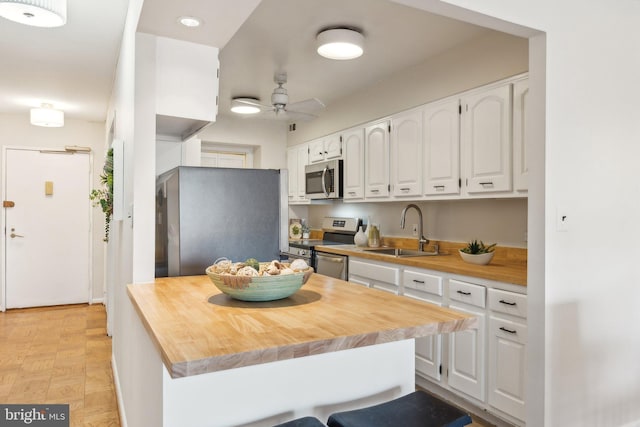 kitchen featuring appliances with stainless steel finishes, white cabinetry, butcher block counters, and sink