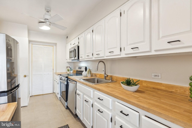 kitchen featuring ceiling fan, sink, stainless steel appliances, light tile patterned floors, and white cabinets