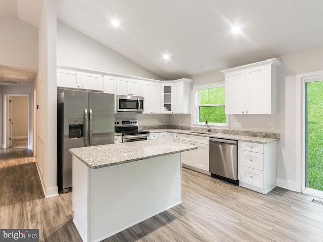 kitchen with appliances with stainless steel finishes, white cabinetry, a kitchen island, and sink