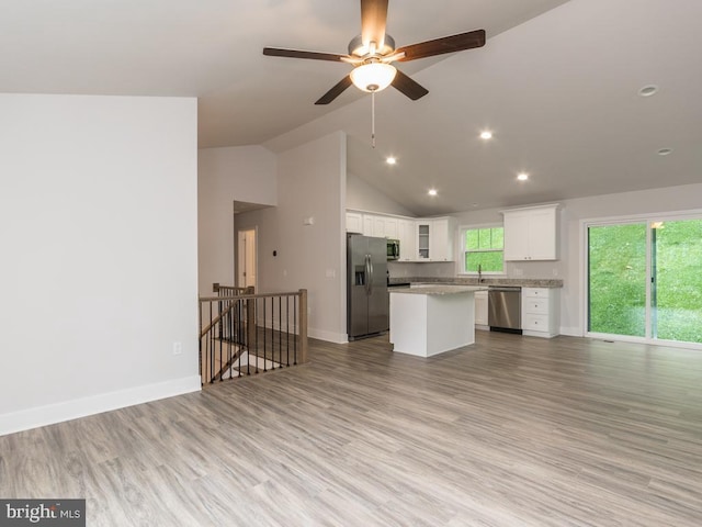 kitchen featuring appliances with stainless steel finishes, vaulted ceiling, ceiling fan, a center island, and white cabinetry