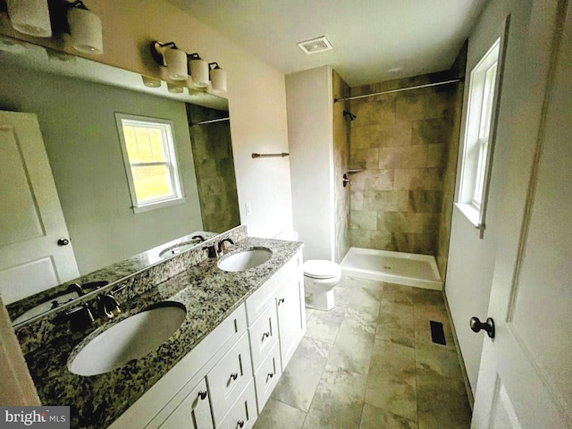 bathroom with vanity, toilet, and a tile shower