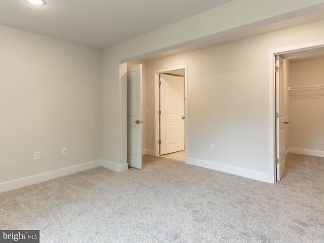 unfurnished bedroom with a spacious closet, a closet, and light carpet