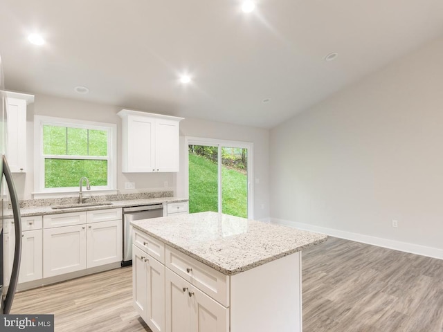 kitchen with dishwasher, a center island, white cabinets, sink, and light stone countertops