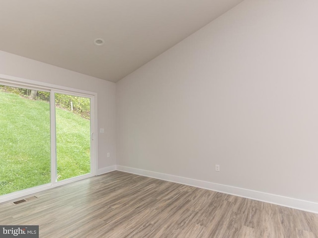 unfurnished room with light hardwood / wood-style floors and vaulted ceiling