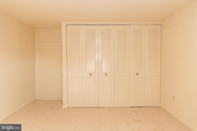 unfurnished bedroom with a closet and light colored carpet