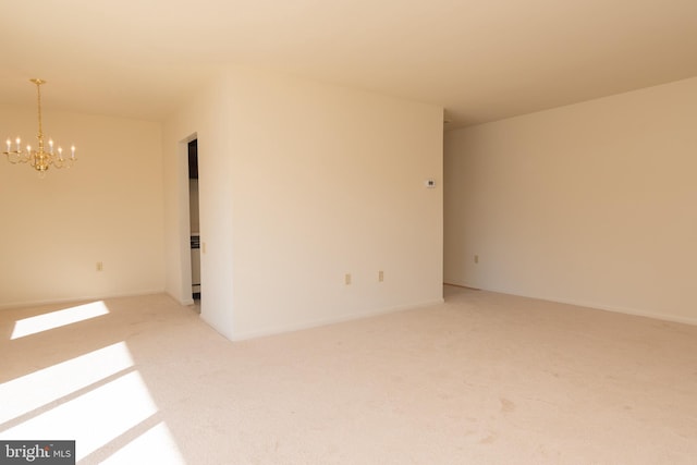 spare room with carpet and an inviting chandelier