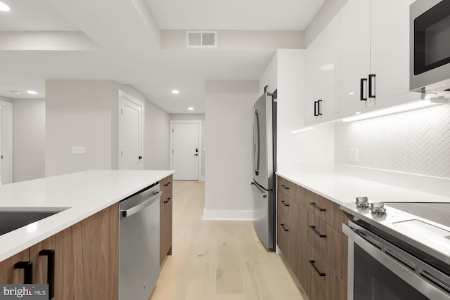 kitchen featuring white cabinets, a barn door, stainless steel appliances, and light hardwood / wood-style flooring