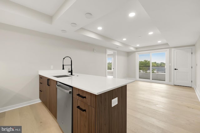 kitchen featuring stainless steel dishwasher, light hardwood / wood-style floors, sink, and a tray ceiling