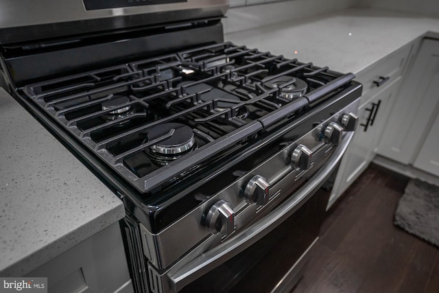 details featuring black gas range and white cabinetry