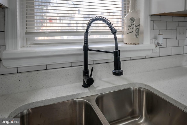 interior details with backsplash, light stone countertops, and sink