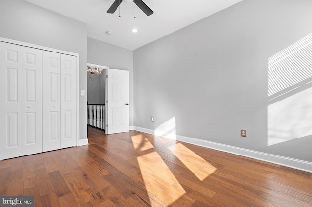 unfurnished bedroom with hardwood / wood-style floors, a closet, ceiling fan, and a high ceiling