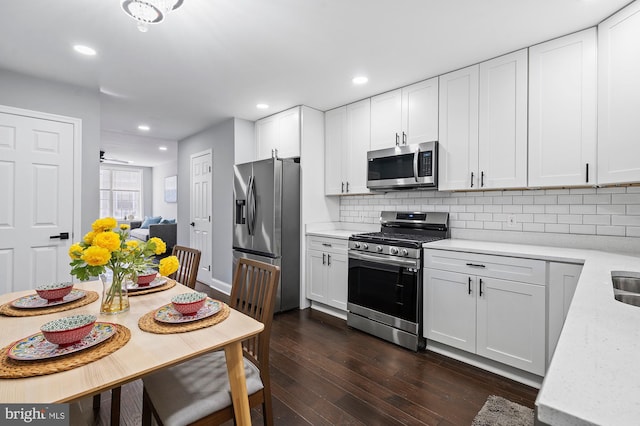 kitchen featuring tasteful backsplash, white cabinetry, stainless steel appliances, and dark hardwood / wood-style floors