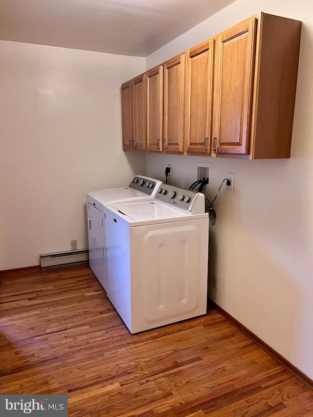 washroom with cabinets, light wood-type flooring, baseboard heating, and washing machine and clothes dryer