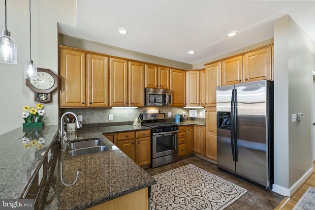 kitchen with dark stone counters, sink, hanging light fixtures, appliances with stainless steel finishes, and kitchen peninsula