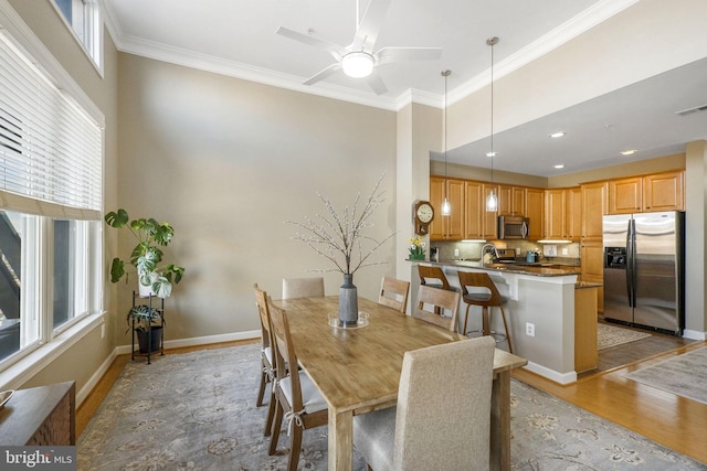 dining space featuring light wood-type flooring, ceiling fan, and ornamental molding