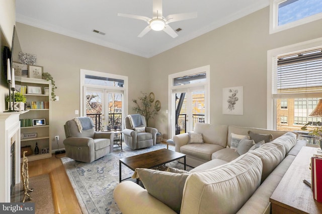 living room with ceiling fan, wood-type flooring, ornamental molding, and french doors