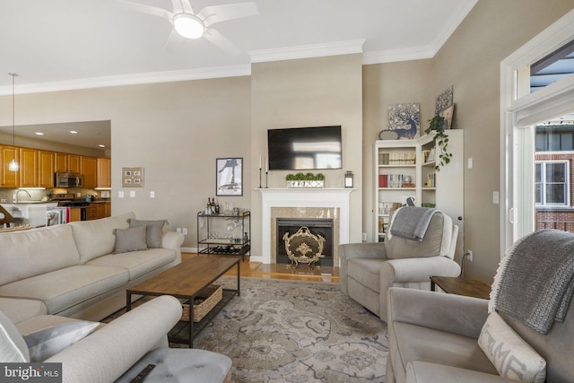 living room featuring ceiling fan, crown molding, and light hardwood / wood-style flooring