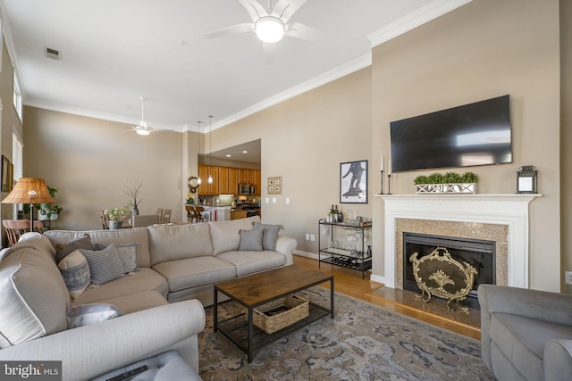 living room featuring hardwood / wood-style flooring, ceiling fan, and crown molding