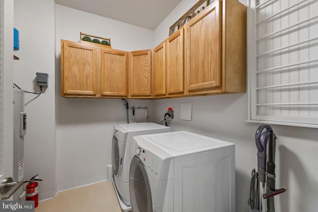 clothes washing area featuring cabinets and separate washer and dryer