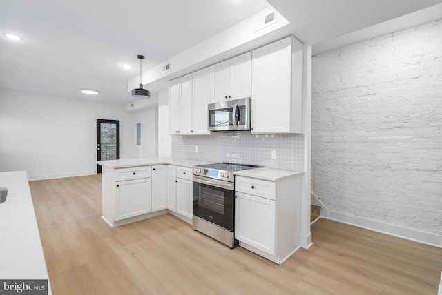 kitchen with white cabinets, light hardwood / wood-style flooring, appliances with stainless steel finishes, decorative light fixtures, and kitchen peninsula