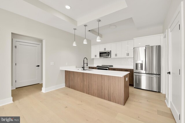 kitchen with pendant lighting, sink, light hardwood / wood-style flooring, appliances with stainless steel finishes, and white cabinetry