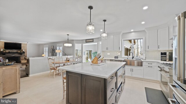 kitchen featuring white cabinets, a fireplace, a center island, and sink