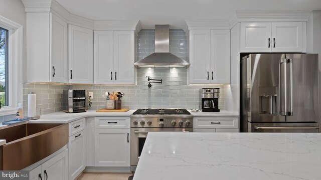 kitchen featuring white cabinetry, wall chimney range hood, light stone counters, decorative backsplash, and high end appliances