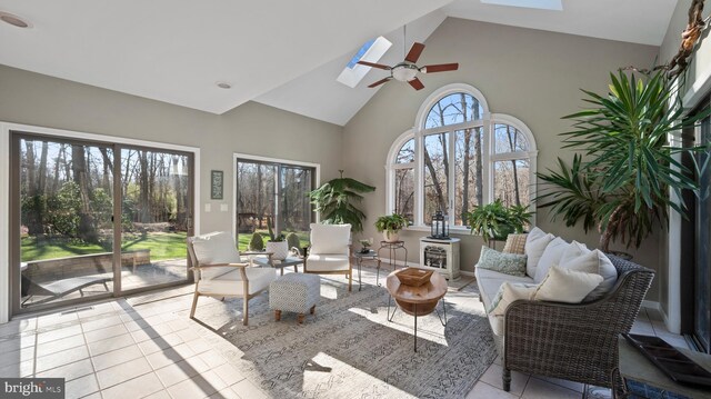 tiled living room with ceiling fan, high vaulted ceiling, and a skylight