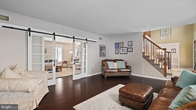 living room featuring a barn door and dark wood-type flooring