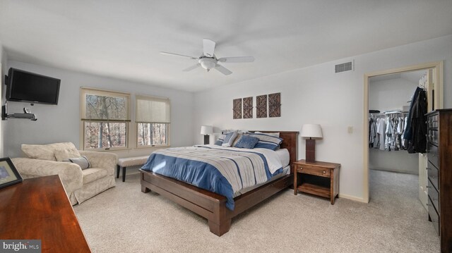 bedroom with light carpet, a closet, a spacious closet, and ceiling fan