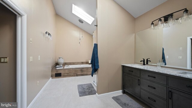 bathroom featuring vaulted ceiling with skylight, vanity, tiled tub, and tile patterned flooring