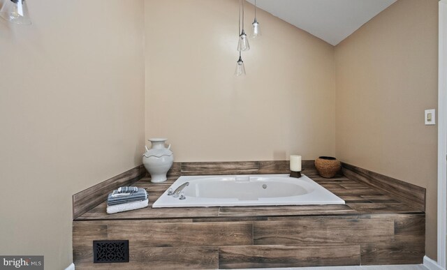 bathroom with a tub and lofted ceiling