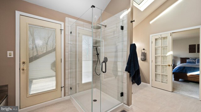 bathroom with vaulted ceiling with skylight, a shower with door, french doors, and tile patterned flooring