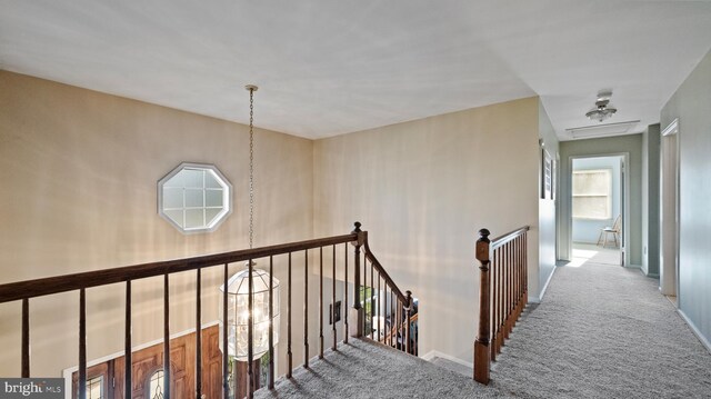 hallway with carpet flooring and an inviting chandelier