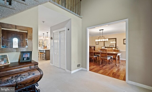 hall featuring wood-type flooring, ornamental molding, and a chandelier